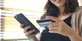 购物女人拿着智能手机和信用卡进行网上购物