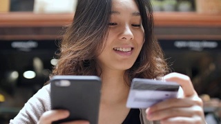 年轻的亚洲女人用智能手机网购，慢镜头视频素材模板下载