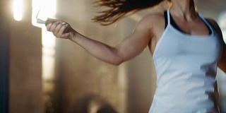 体育美女在健身房里用跳绳练习。她正在进行部分高强度的健身训练。
