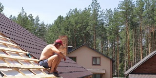 屋顶工人坐在屋顶上进行控制测量。