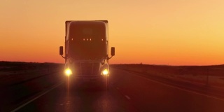 近距离镜头光晕:在金色的夕阳下，半卡车直接撞向摄像机