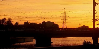 俄罗斯阿斯特拉罕的清晨。老城桥上的汽车和行人。橙色的太阳