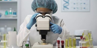 在实验室用显微镜观察微生物样本的医学科学家