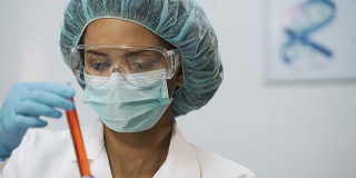 穿着医疗制服的妇女正在测试新疫苗分析试管中的液体