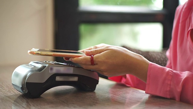 一名女性在咖啡馆用智能手机支付近场通信技术。