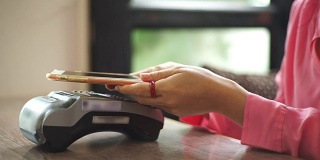一名女性在咖啡馆用智能手机支付近场通信技术。