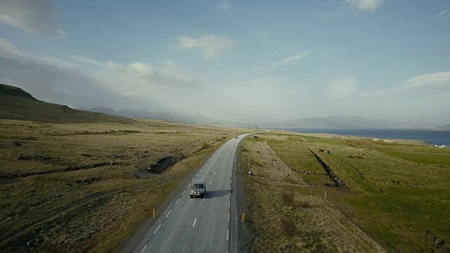 直升飞机在交通道路上飞过，汽车在上面行驶。田野和海岸的美丽风景