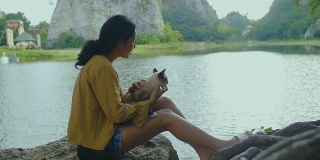 一个年轻女子和一只猫坐在一块石头上