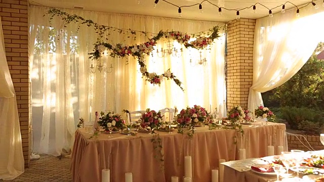 婚礼餐桌的乡村风格装饰与盘子，饮料和鲜花在粉红色和米黄色。宴会餐桌上玫瑰的植物组成