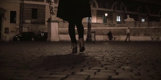 女性的脚在晚上走过荒芜的街道的特写镜头。孤独的女人回家晚了