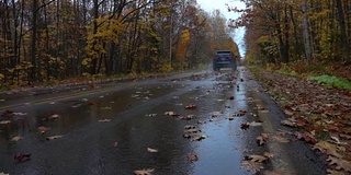 慢镜头近景:黑色SUV汽车潜水在湿滑的道路槽森林