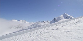 慢动作:年轻的职业滑雪板在半管雪公园跳过太阳
