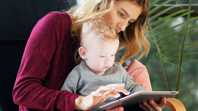 母亲和婴儿在家里使用数码平板电脑4k