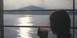 一名年轻女子坐在货轮的长椅上，用纸杯喝茶，眺望着大海。1920 x1080