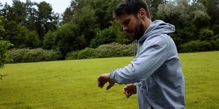 男人在绿色公园的树林里跑步训练和看智能手表