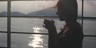 年轻女孩沉思地坐在货运渡轮的长椅上，用纸杯喝着咖啡，望着大海。1920 x1080
