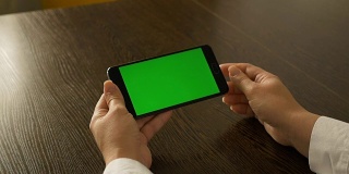 一个女人拿着绿色屏幕的手机。为您的视频内容。
