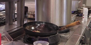 厨师将食材放入厨房烤锅中，在空气中搅拌