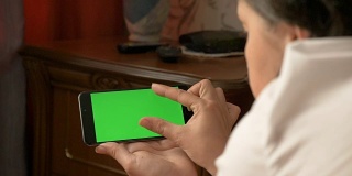 一名女子躺在床上，手里拿着绿色屏幕的智能手机。