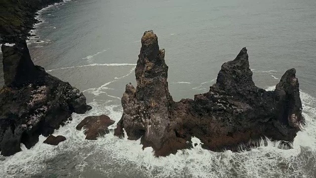 鸟瞰冰岛的山脉巨怪脚趾，海鸥在上面筑巢。直升机在黑海滩的悬崖上盘旋