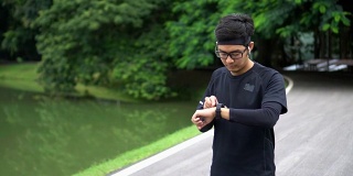 亚洲男子开始慢跑使用他的心率运动手表在自然公园