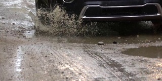 慢镜头近景:一辆SUV在泥泞的道路上行驶