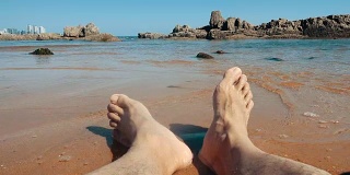 男人的腿躺在沙滩上