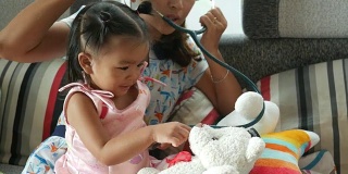 亚洲婴儿扮演医生和病人与母亲