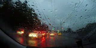 夜雨在城中行驶时光流逝。夜晚的道路POV透过挡风玻璃看雨点在夜晚的城市时光流逝