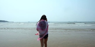 在海滩上围着围巾的女人