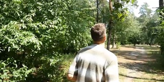 一个穿着条纹t恤和黑色裤子的活跃男子慢镜头在森林里奔跑
