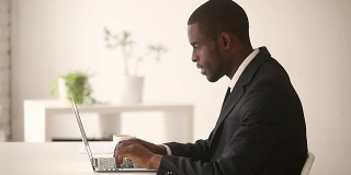 非裔美国商人坐在办公桌前用电脑工作