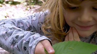 小女孩抱着的叶子上的绿毛虫视频素材模板下载