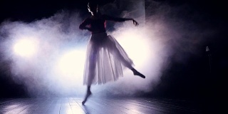 芭蕾舞者在黑暗中跳跃。