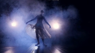 一位女舞者匆匆穿过黑暗的舞台。视频素材模板下载