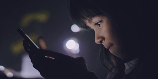 小女孩晚上在卧室里玩手机。