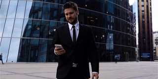 英俊的企业家在商业中心使用iphone上的应用程序阅读短信或信使