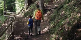 小儿子和妈妈在森林小路上徒步旅行