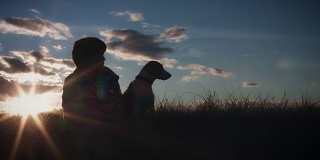 4K户外剪影的孩子和狗看日落