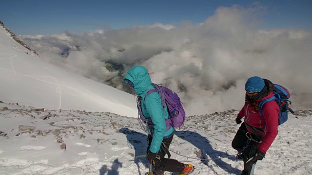 两名女登山家在云上微笑着攀登冰川。