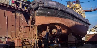 工人们在船厂的浮船坞修理旧船。船舶螺旋桨重建。渔船焊接延时全高清视频