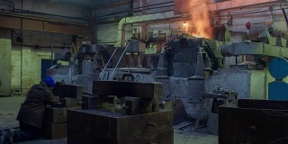 在铸造车间辛勤工作，工人在熔炉中控制铁的冶炼，工作环境太热、冒烟。金属铸造视频全高清视频延时