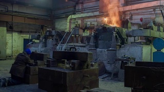 在铸造车间辛勤工作，工人在熔炉中控制铁的冶炼，工作环境太热、冒烟。金属铸造视频全高清视频延时视频素材模板下载