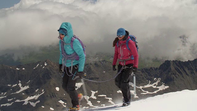 为了安全，两名女登山队员用绳子系在一起，徒步穿越冰川。