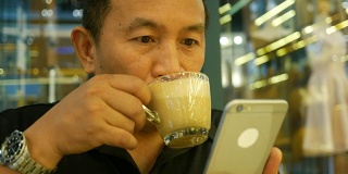 成熟的男人在咖啡店用手机
