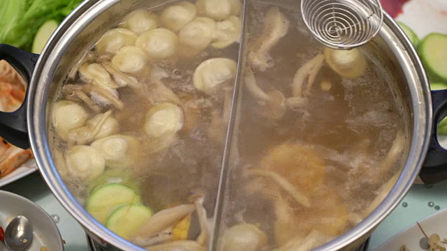 概念火锅家庭烹饪。从沸腾的汤中取出玉米、蘑菇和饺子
