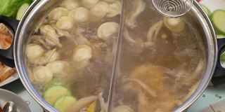 概念火锅家庭烹饪。从沸腾的汤中取出玉米、蘑菇和饺子