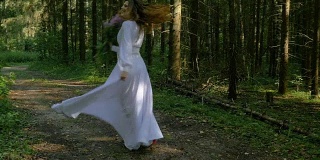一个漂亮的女孩穿着白色的裙子和长发在公园跳舞。她很高兴，大笑，微笑，转身。