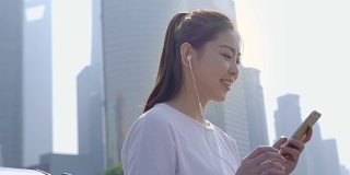 年轻的亚洲女人在户外听音乐