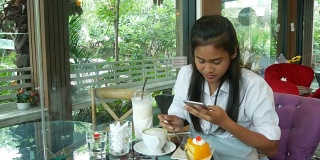 亚洲少女在咖啡店用手机